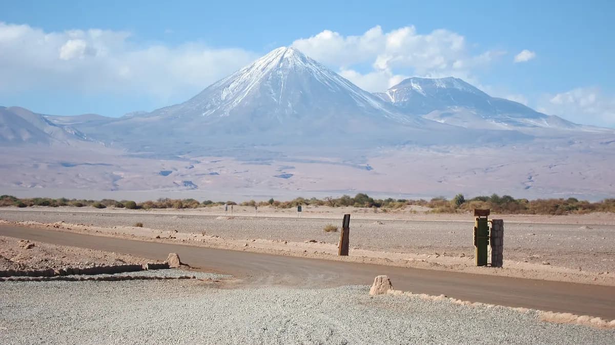 Volcanes nevados sobre el desierto de Atacama, con un camino de tierra en primer plano
