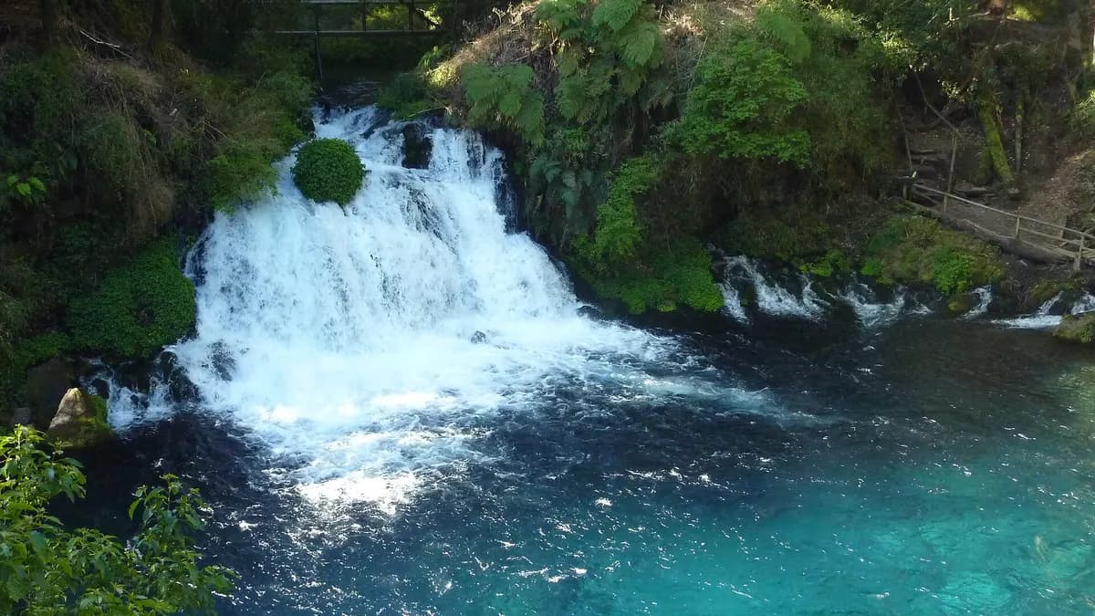 Cascada que cae en una poza de agua turquesa rodeada de bosque en los Ojos del Caburgua