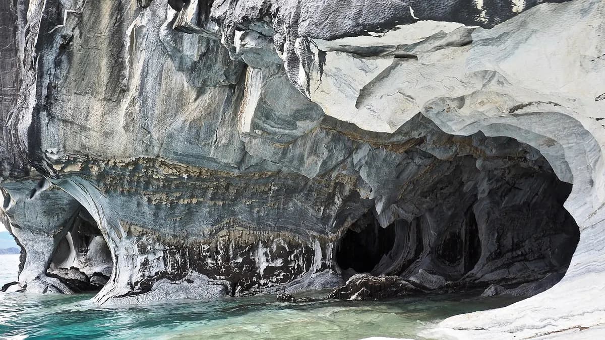 Caverna de mármol con vetas grises y blancas sobre agua turquesa en el lago General Carrera