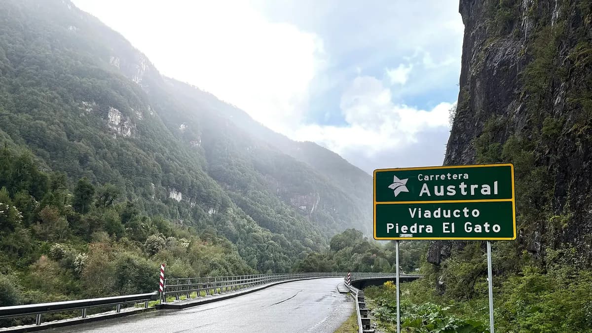 Viaducto Piedra El Gato en la Carretera Austral con cerros boscosos y señalética