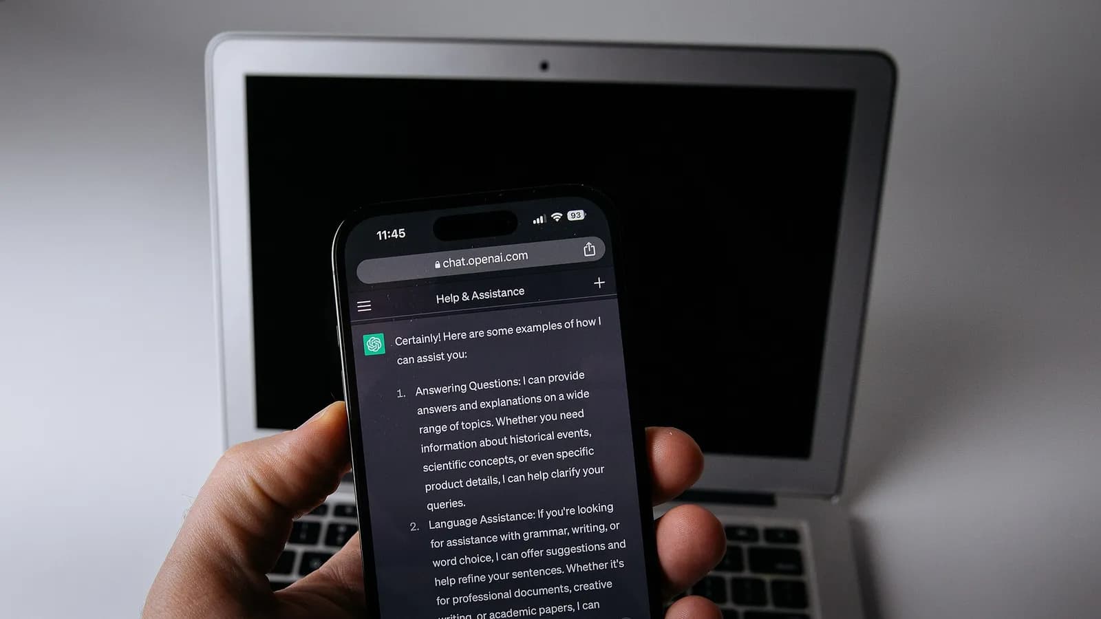 Smartphone con la app de ChatGPT junto a un computador portátil