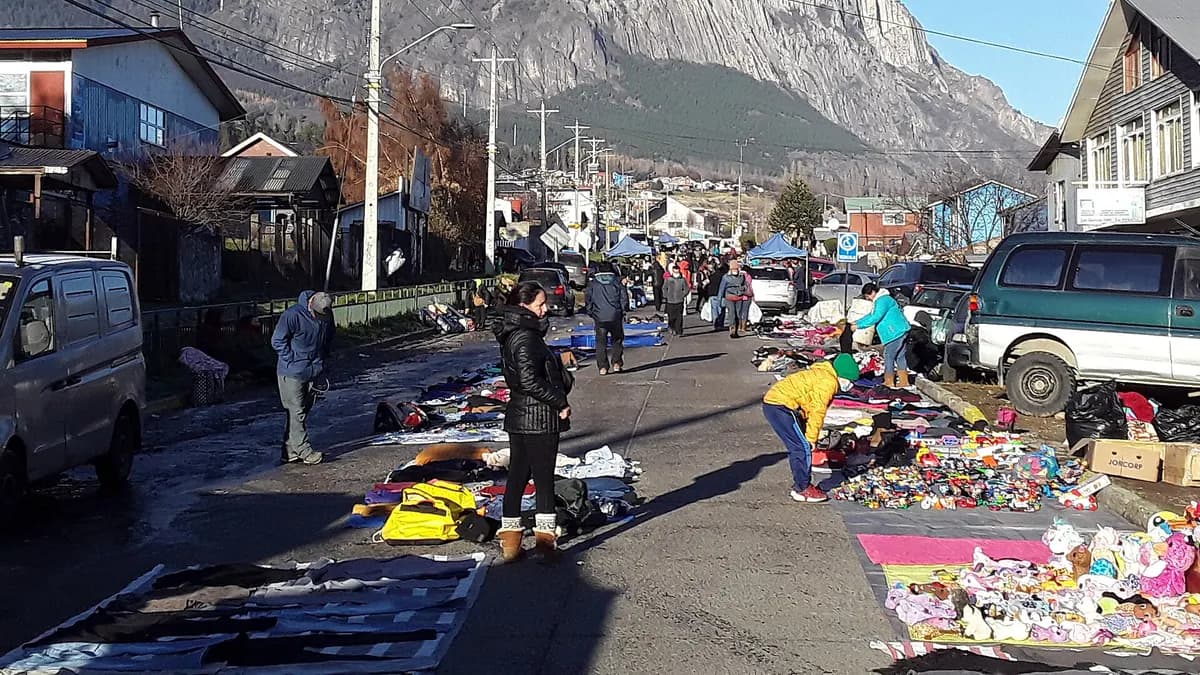 Puestos de una feria al aire libre en una calle de Coyhaique con cerros al fondo