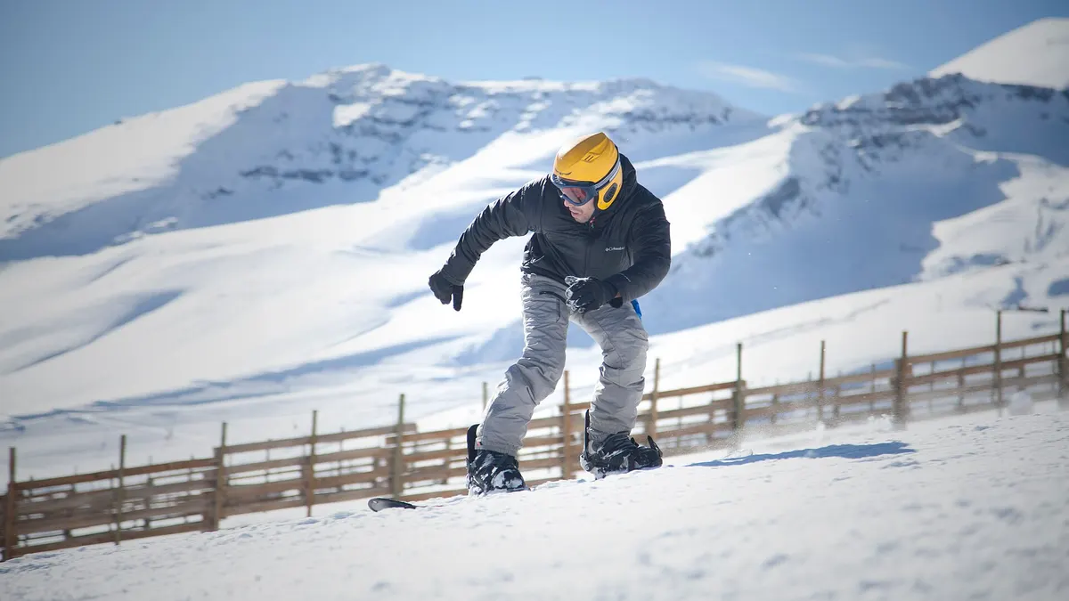 Snowboarder en una pista del centro de ski El Colorado, con la cordillera nevada al fondo