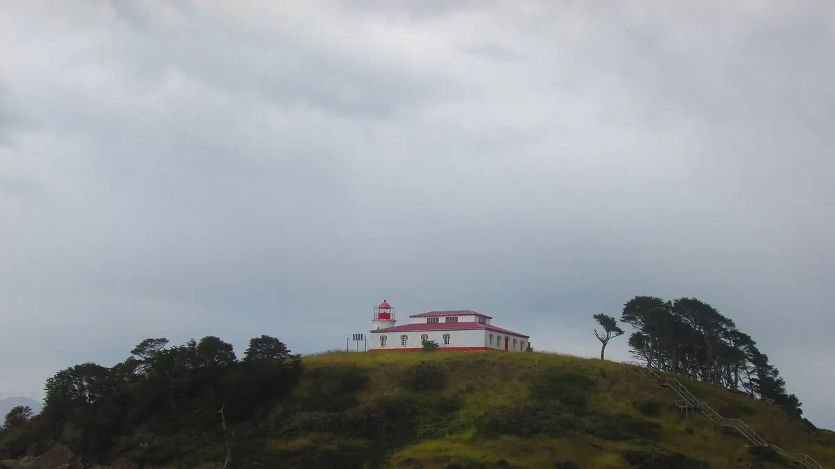 Faro San Isidro, de color blanco y rojo, sobre una península verde en el estrecho de Magallanes