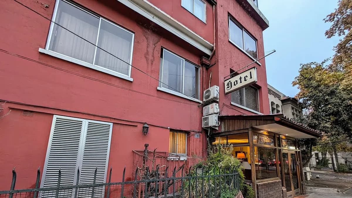 Fachada de un hotel pequeño de color rojo en una calle de Santiago