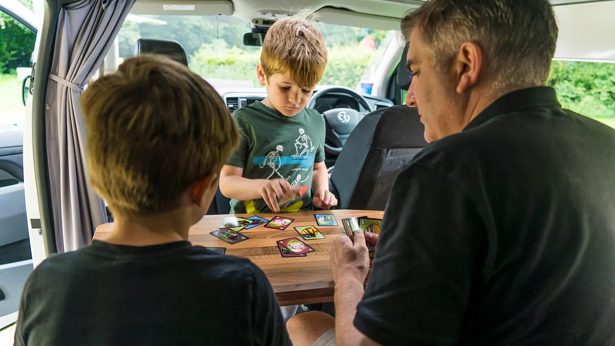 Una familia juega a las cartas en la mesa de una casa rodante durante un viaje