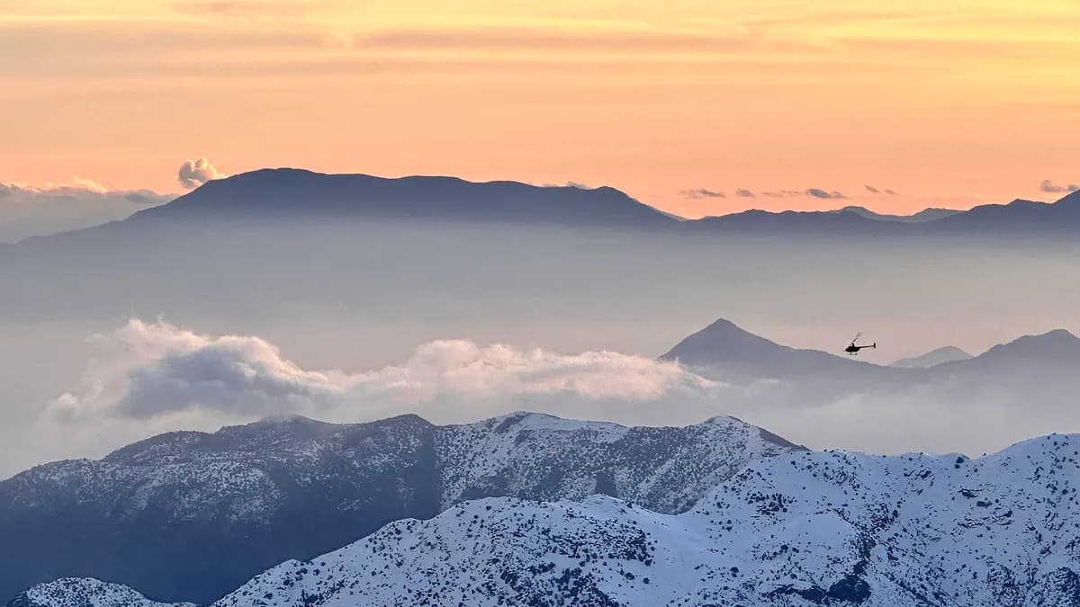 Cordillera nevada sobre un mar de nubes al atardecer, vista desde La Parva