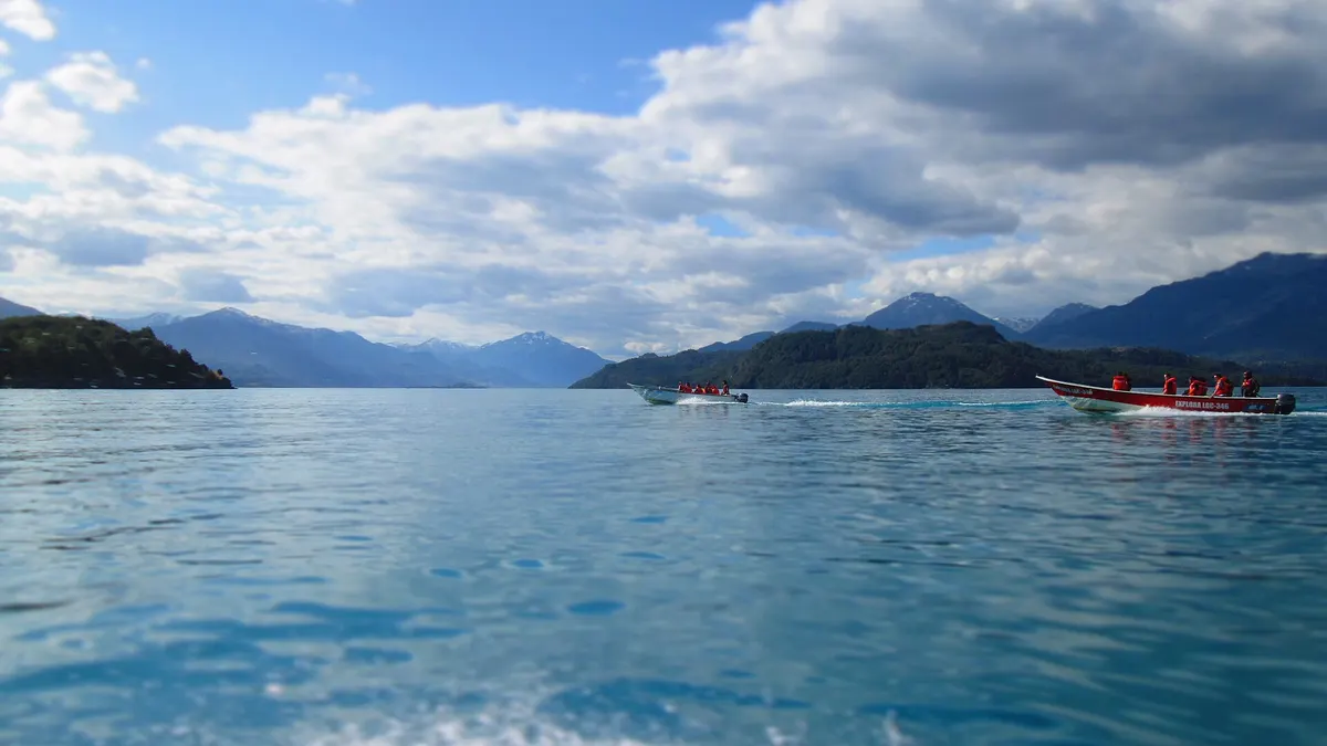 Lanchas navegando en las aguas azules del lago General Carrera con montañas al fondo