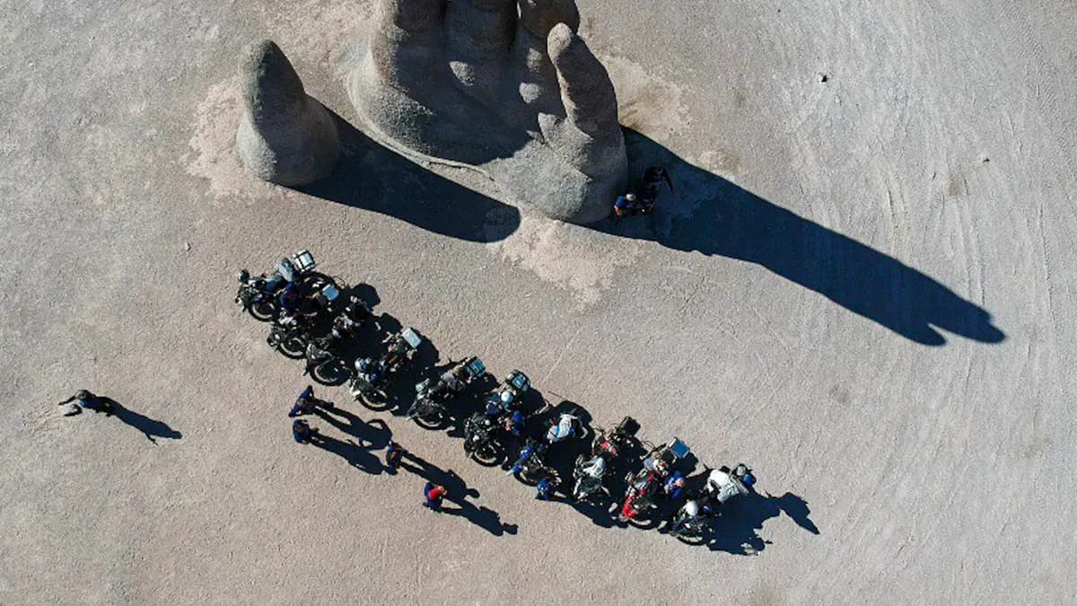 Vista aérea da Mão do Deserto com um grupo de motociclistas ao lado