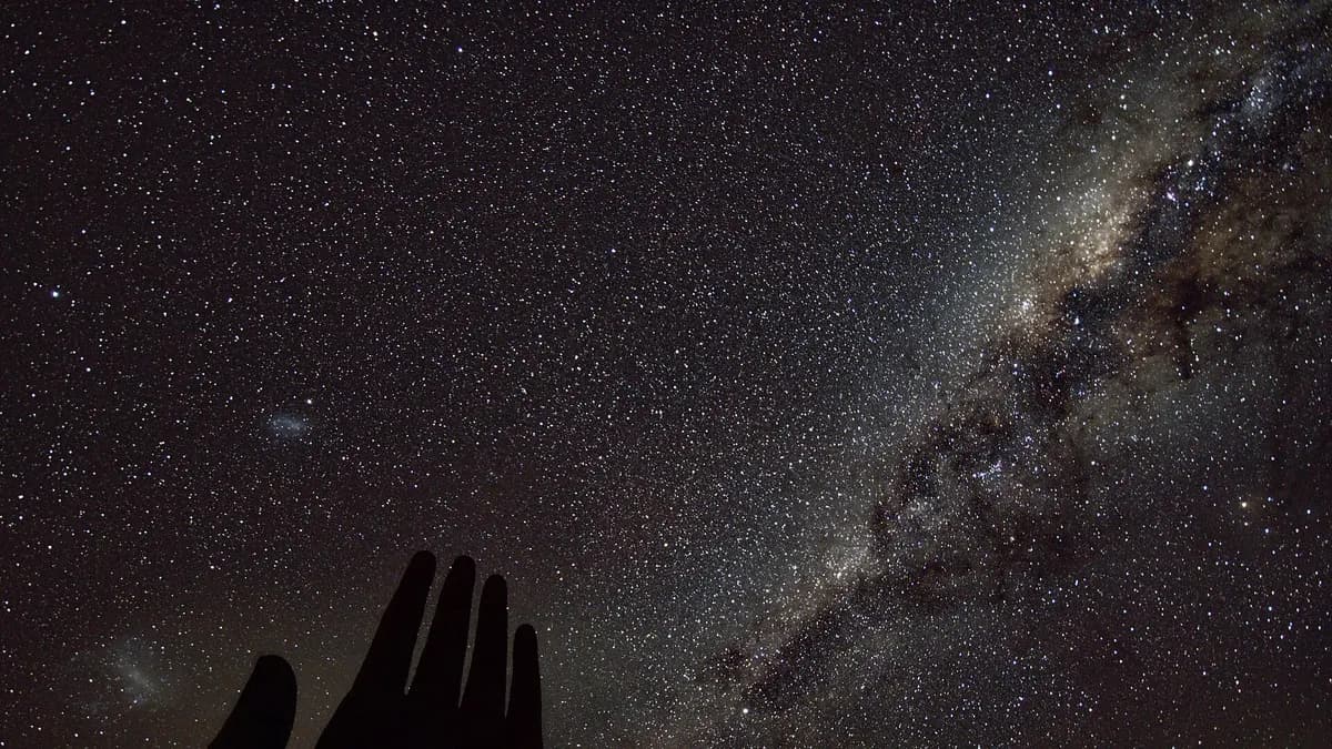 A Via Láctea sobre a silhueta da Mão do Deserto à noite