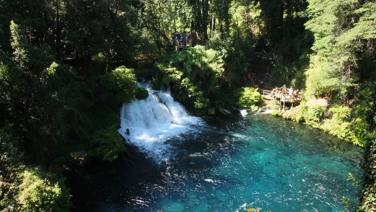 Cascada que cae en un pozón de agua turquesa entre el bosque en los Ojos del Caburgua