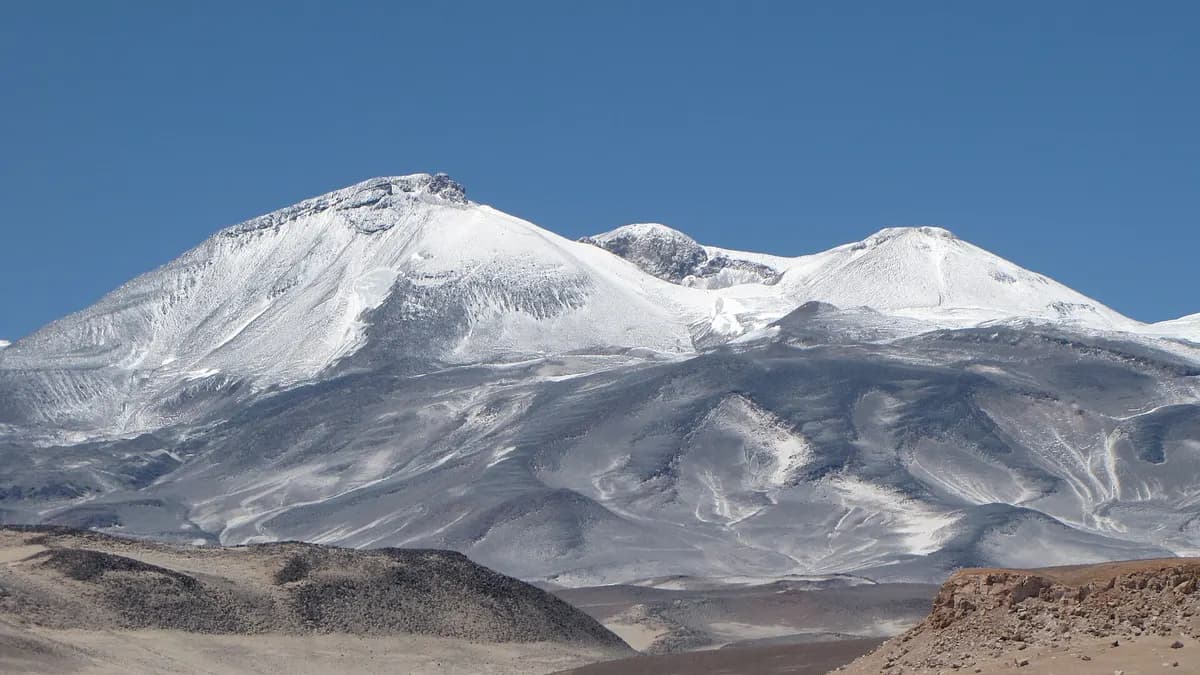 Volcán Ojos del Salado con laderas grises y nieve bajo un cielo azul en el altiplano de Atacama