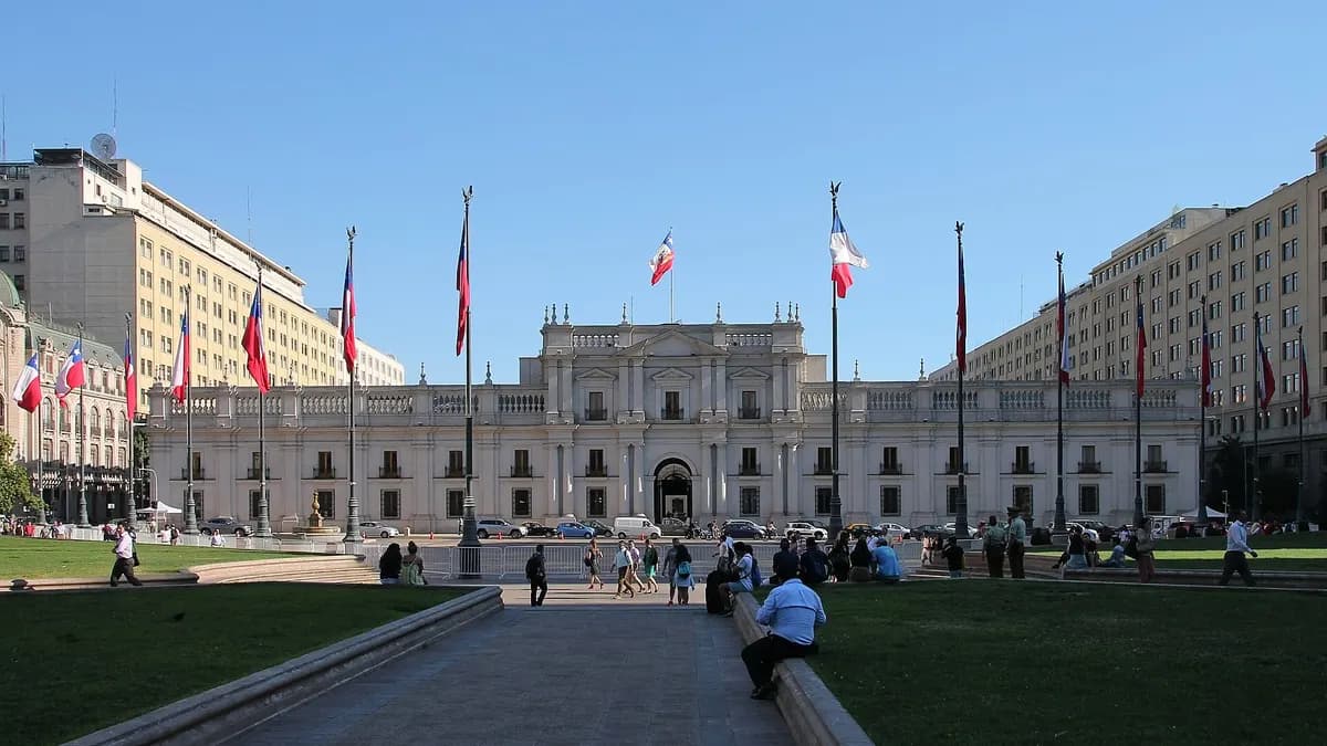 Fachada neoclásica del Palacio de La Moneda con banderas chilenas y la plaza de la Constitución