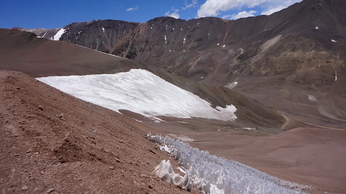 Ladera de alta montaña con un manto de nieve y hielo junto al camino de tierra del paso Agua Negra