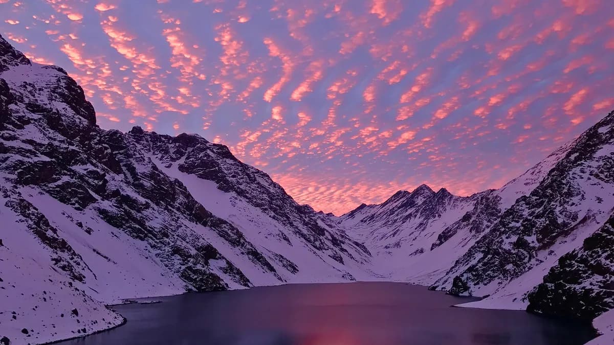 La Laguna del Inca rodeada de montañas nevadas bajo un cielo rosado al atardecer