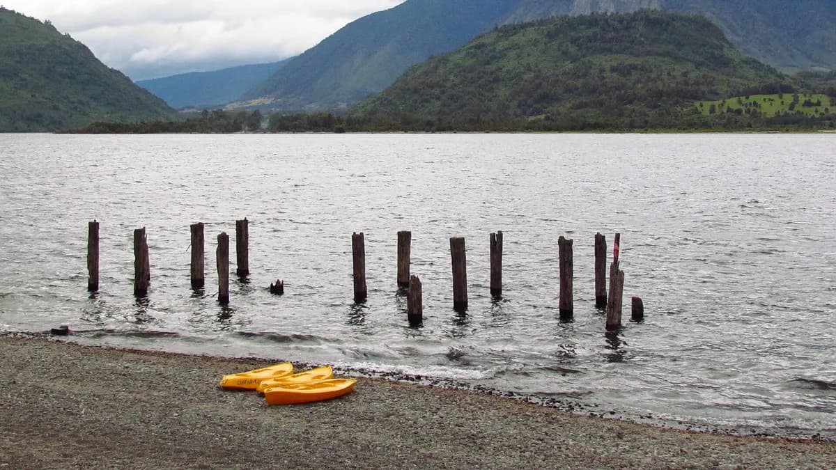 Restos de un antiguo muelle en la playa Huequecura, en Llifén, con cerros boscosos al fondo