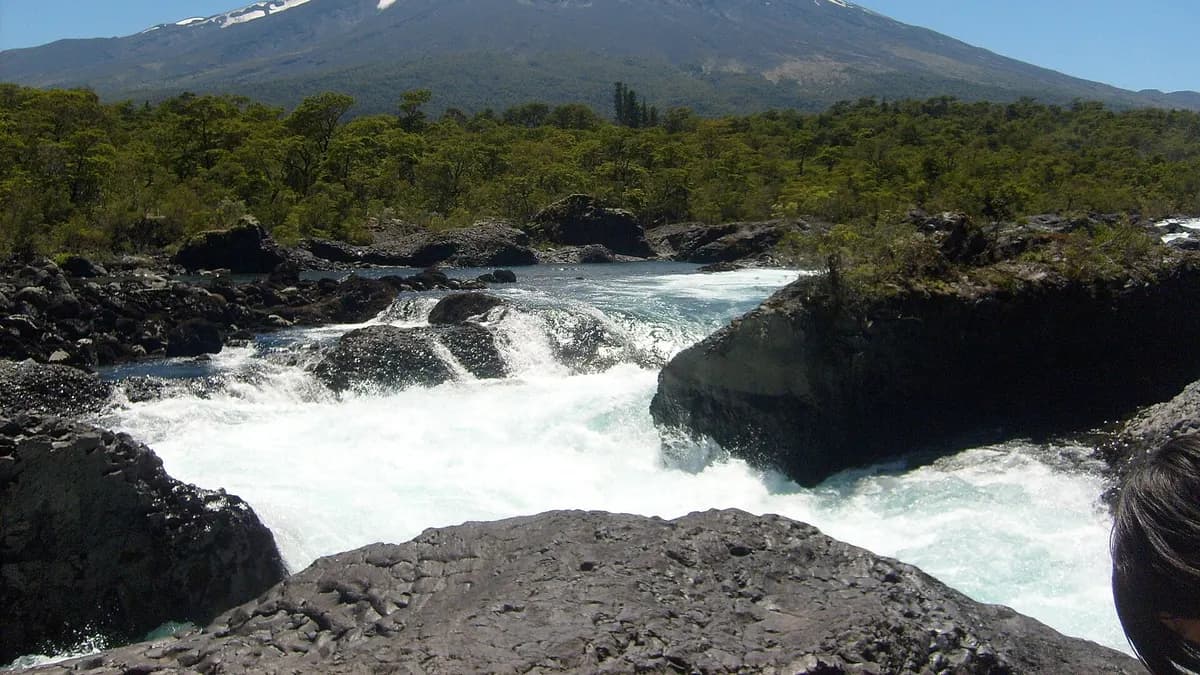 Saltos del Petrohué con agua turquesa sobre roca volcánica y el volcán Osorno nevado al fondo