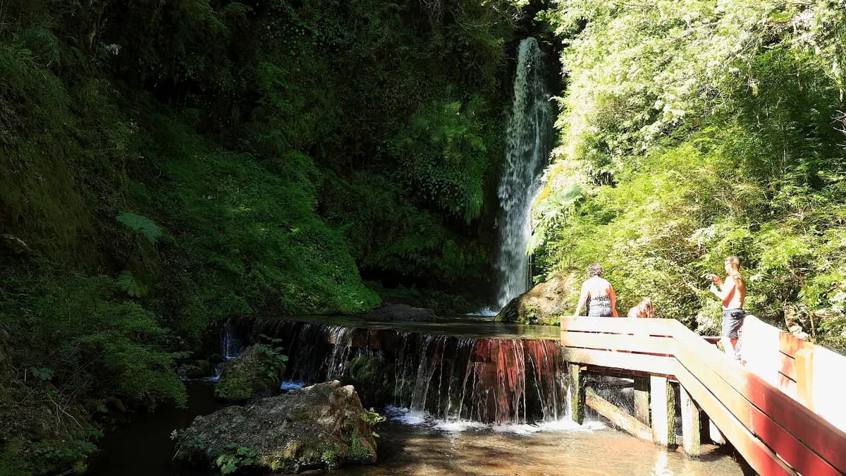 Cascada que cae sobre un pozón de las Termas Geométricas junto a la pasarela de madera roja